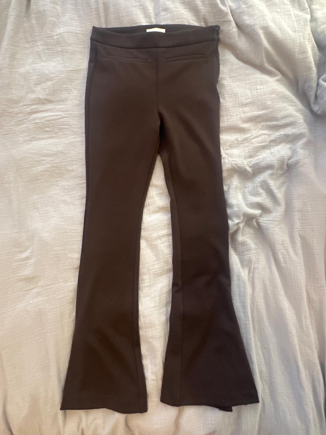 Black flared trousers on a wrinkled grey fabric surface.