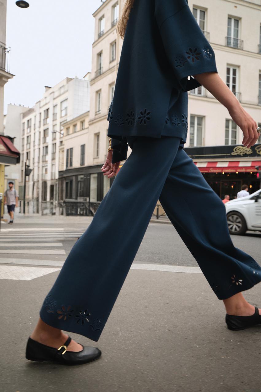 Medium shot of royal blue pants with wide legs and perforated embroidery at the hem.