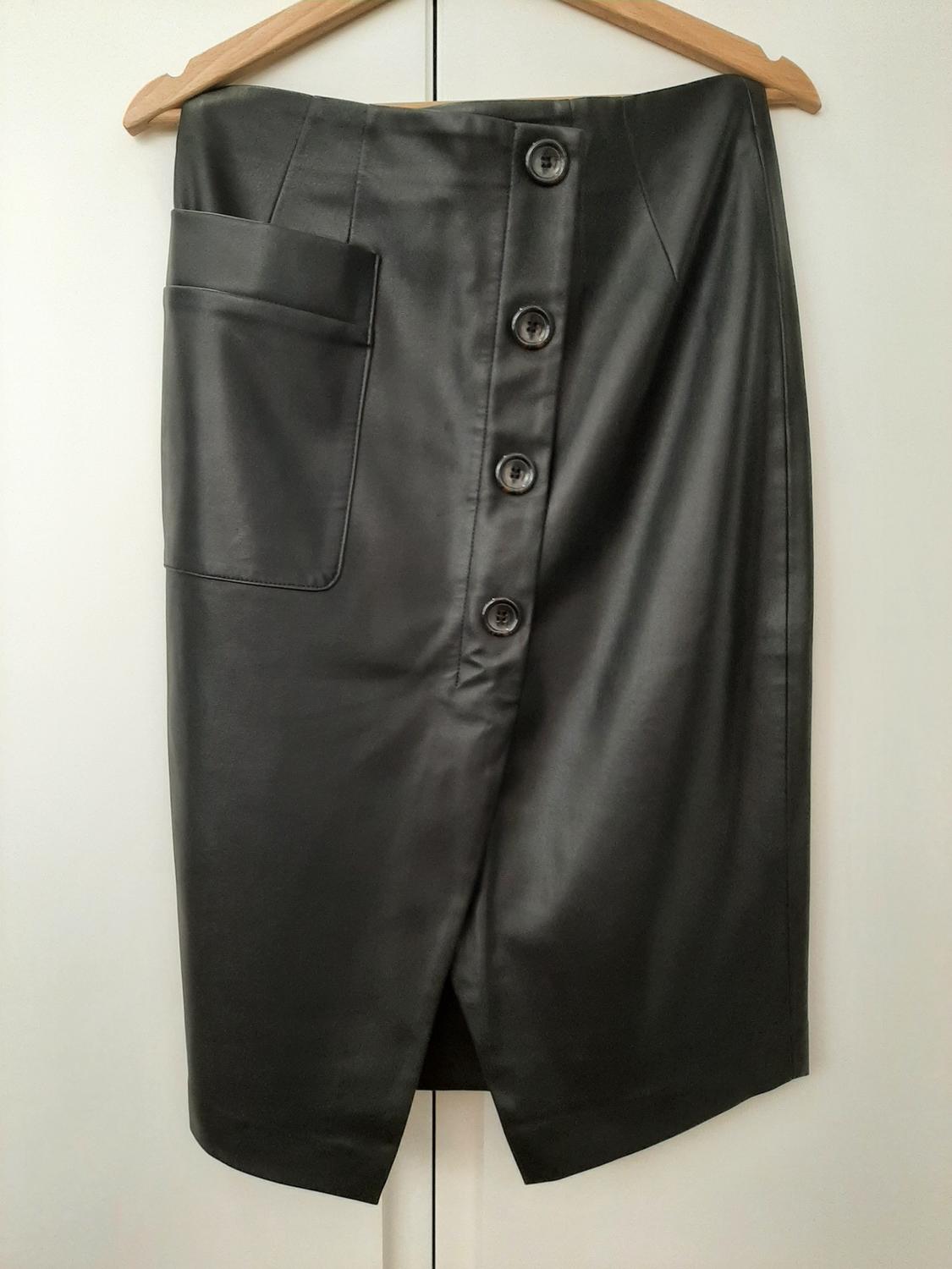 Front view of a black skirt with buttons and a side pocket.