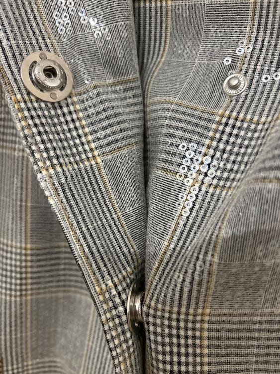 Grey checked fabric with sequins and metallic buttons. Close-up detail of texture and design.