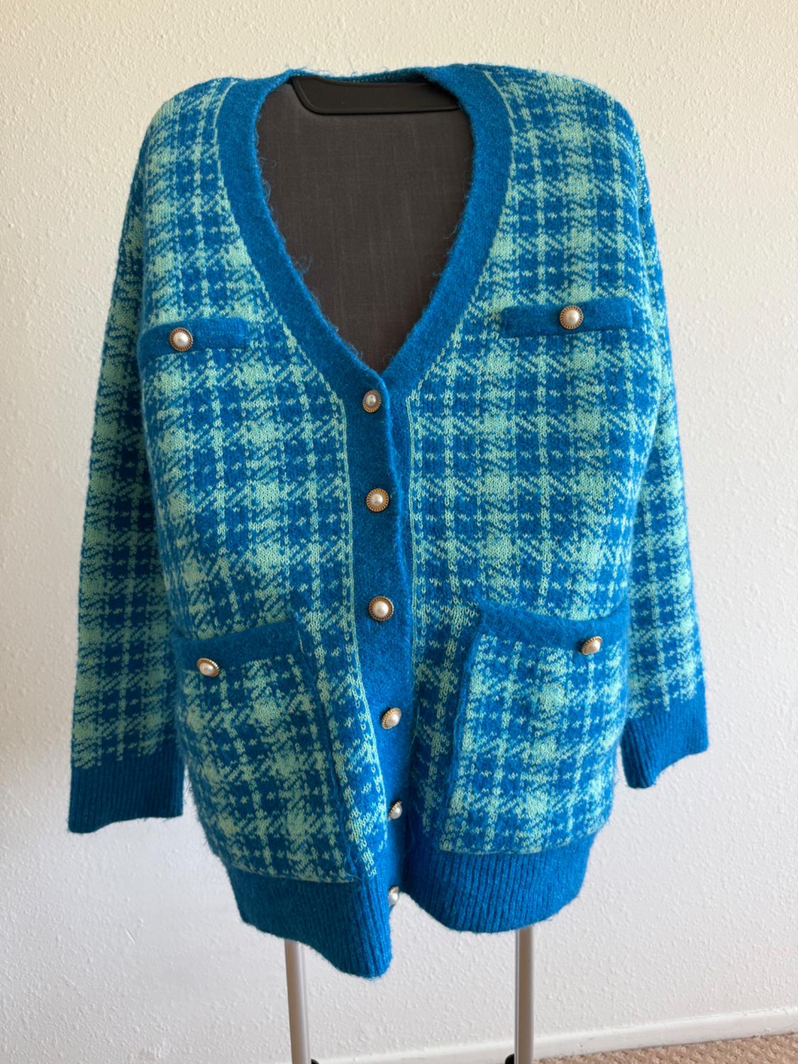 Blue cardigan with a checked print, gold buttons, and pockets, displayed on a mannequin against a white background.