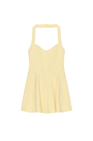 Front view of a short yellow dress with a halter neck and sweetheart neckline. Defined seams and concealed button fastening.