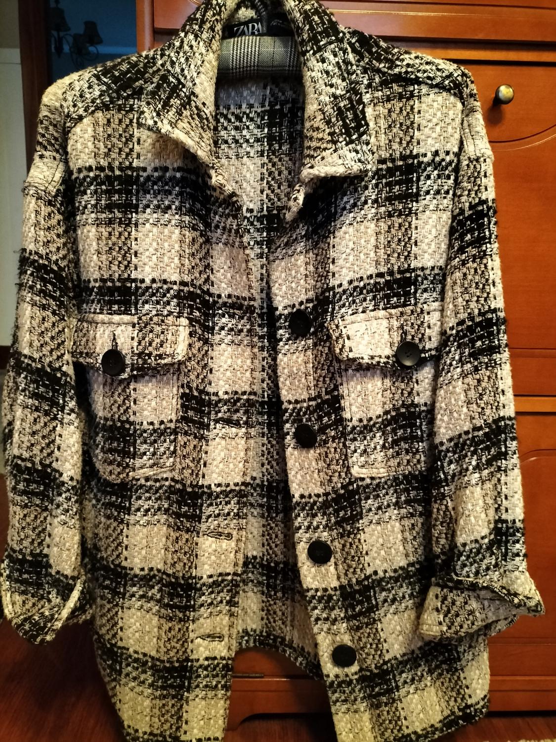 Front view of a black and white checked jacket with front flap pockets and large buttons.