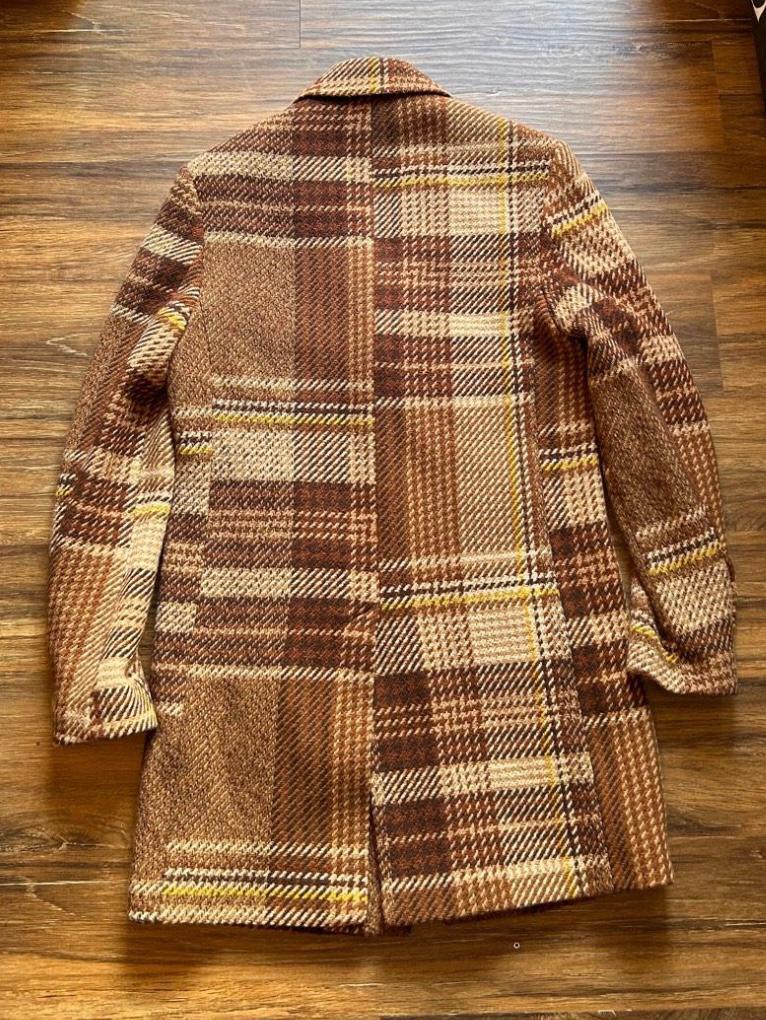 Back view of a brown and beige checked coat with a large check design, straight cut, and long sleeves.