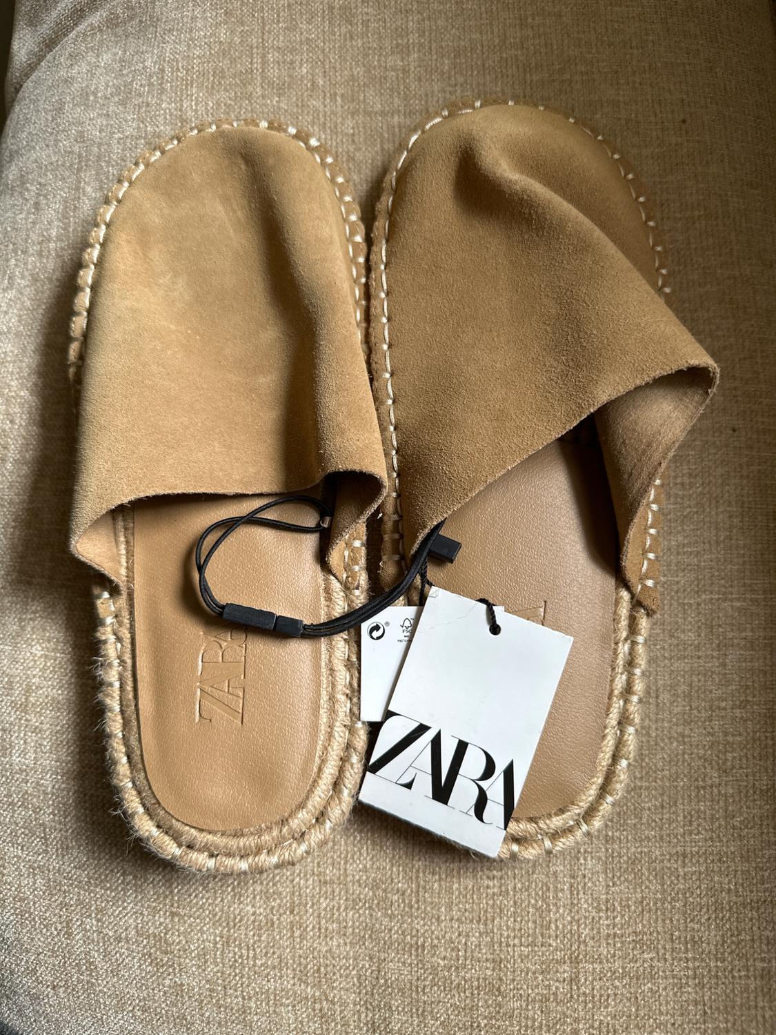Backless brown suede sandals with a jute sole on beige fabric. ZARA text visible on the label.