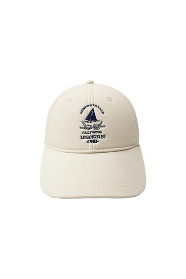 Front view of a beige cap with 'NEWPORT BEACH CALIFORNIA LOS ANGELES 1983' embroidery and a sailboat.