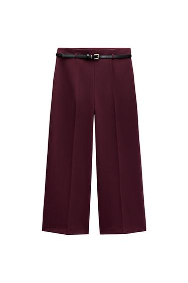 Front view of burgundy trousers with black belt and gold buckle.