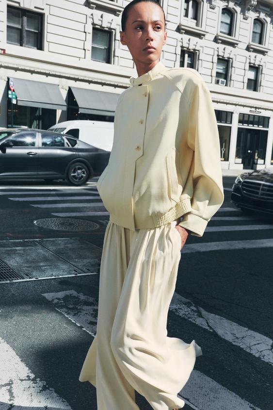 Béžový komplet: sako s knoflíky a bočními kapsami, široké kalhoty ve stejném stylu.