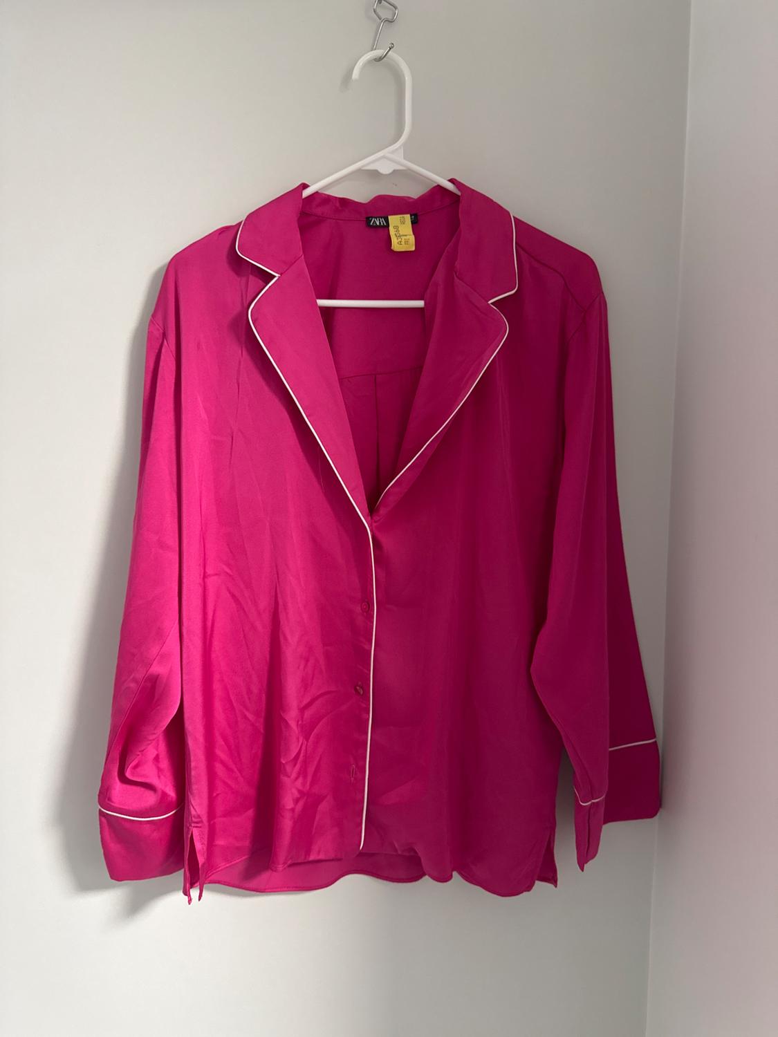 Front view of a fuchsia blouse with white trim, a lapel collar, and front buttons.