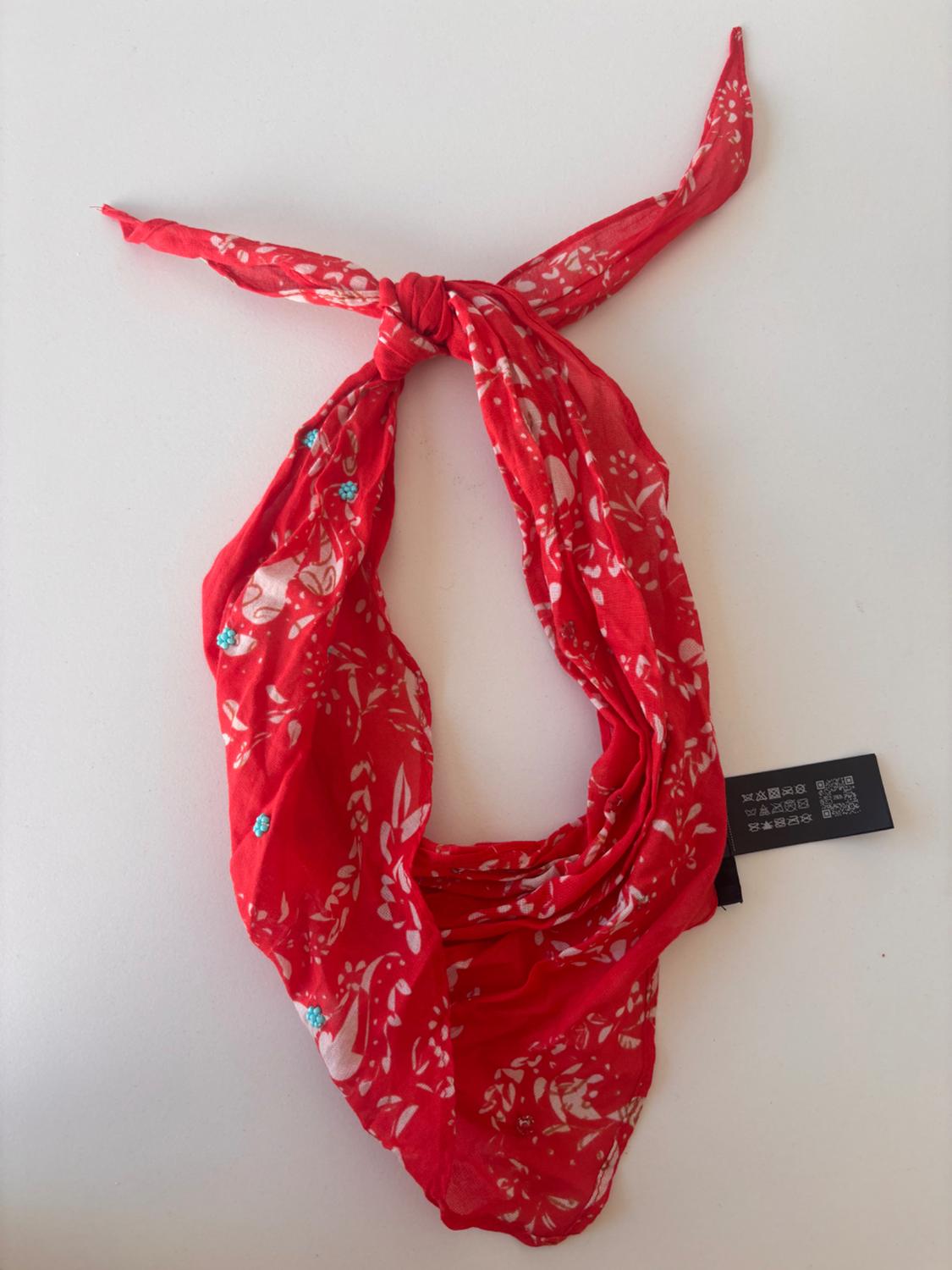 Red scarf with a white floral print and blue details, tied at the top, on a white background. Label visible on the right.