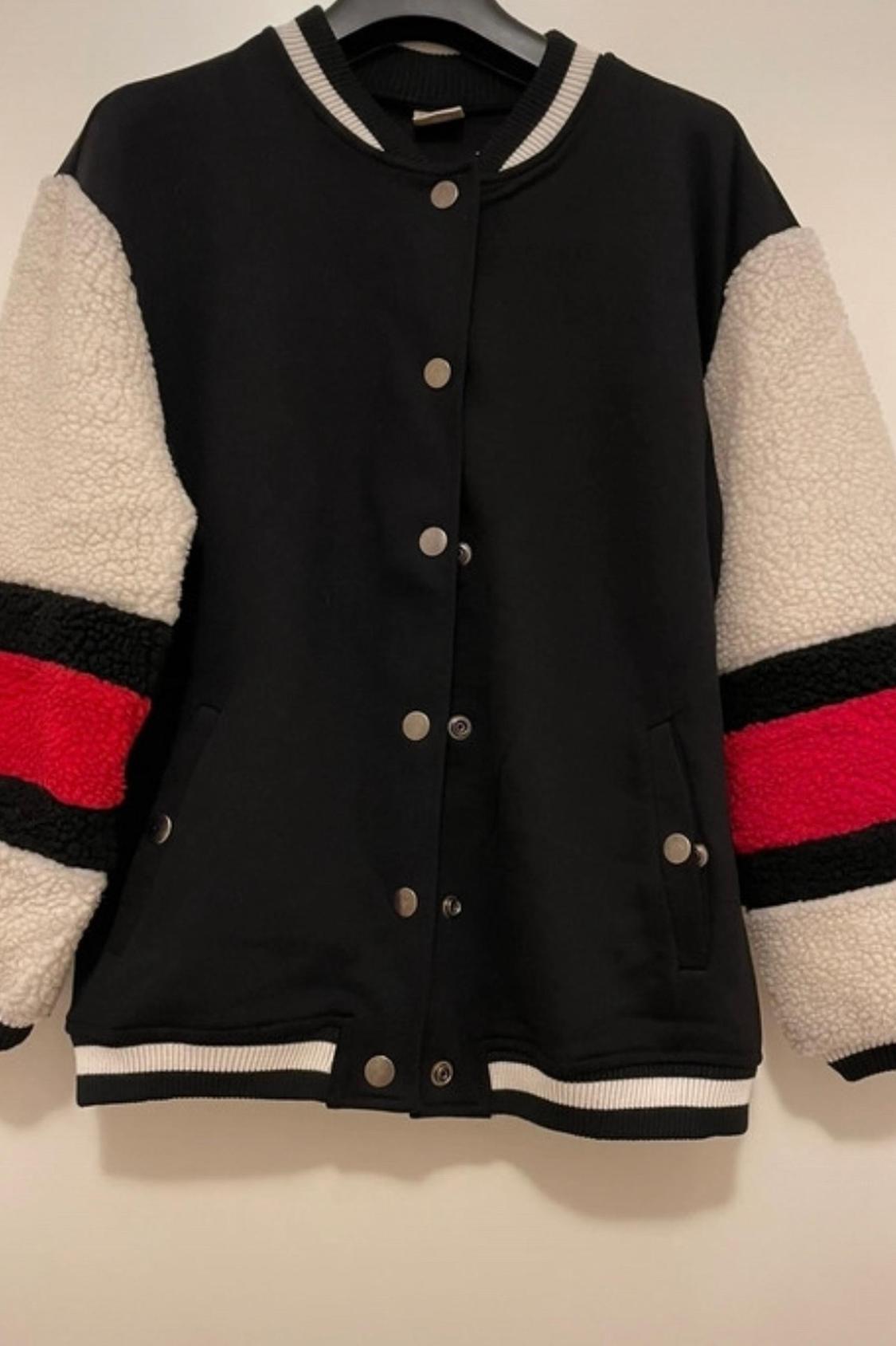 Front view of a black jacket with white wool sleeves and red and black stripes, metal buttons and side pockets.