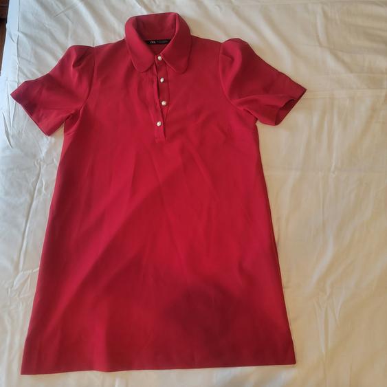 Red short-sleeved dress with a round neck and white buttons, on a white surface.