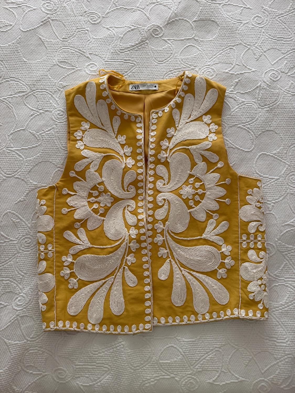 Yellow waistcoat with white floral embroidery on textured white fabric. ZARA label on the inside neck. Relaxed fit.