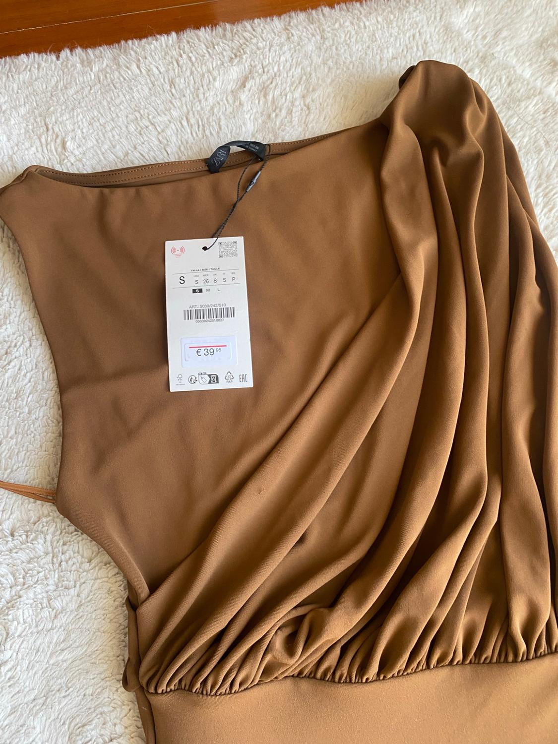Brown asymmetric draped top against a white background. Text on label: ZARA S ART.: 5039/242/510 € 39.95.