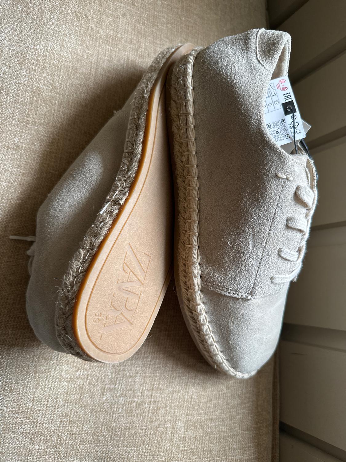 Beige casual lace-up shoes on fabric. One shows the sole with the text ZARA 39 and the other has a label with EAC.