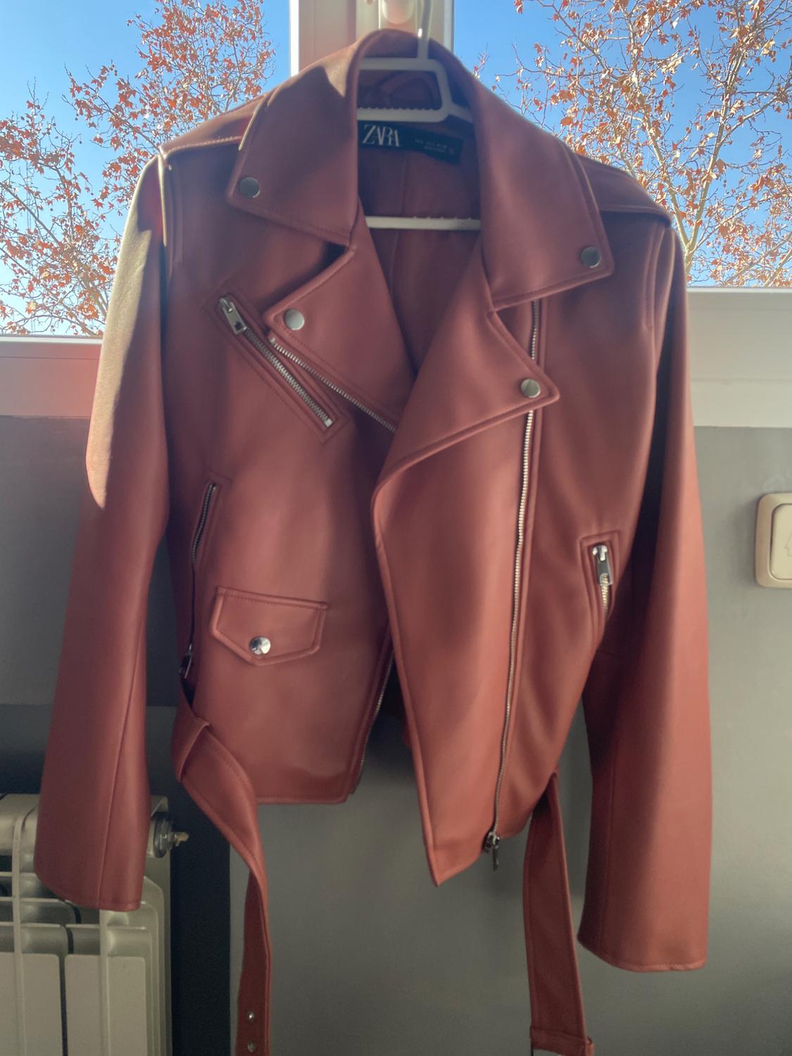 Front view of a brown jacket with lapels and silver zips.