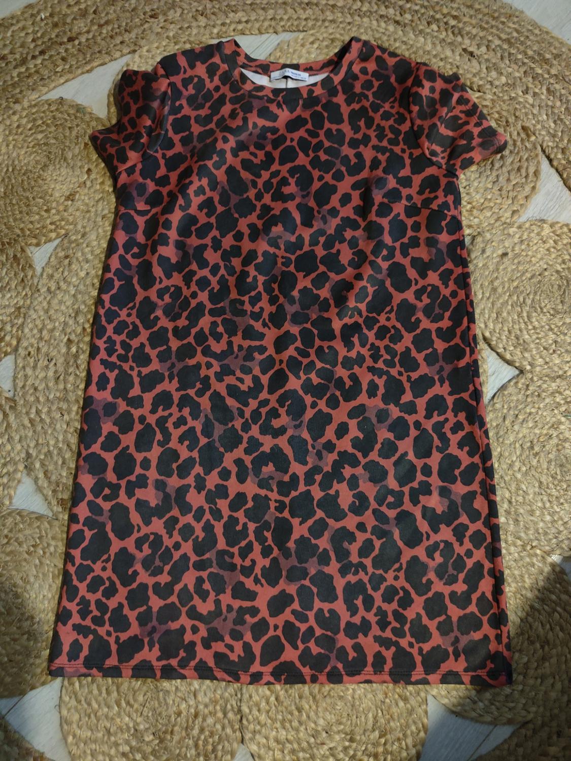 Short animal print dress in black and brown tones on a braided jute rug.