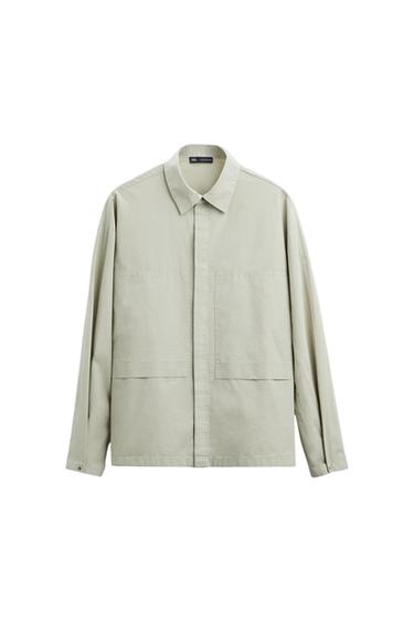 Beige long-sleeved shirt with a classic collar and large front pockets, hanging against a white background.