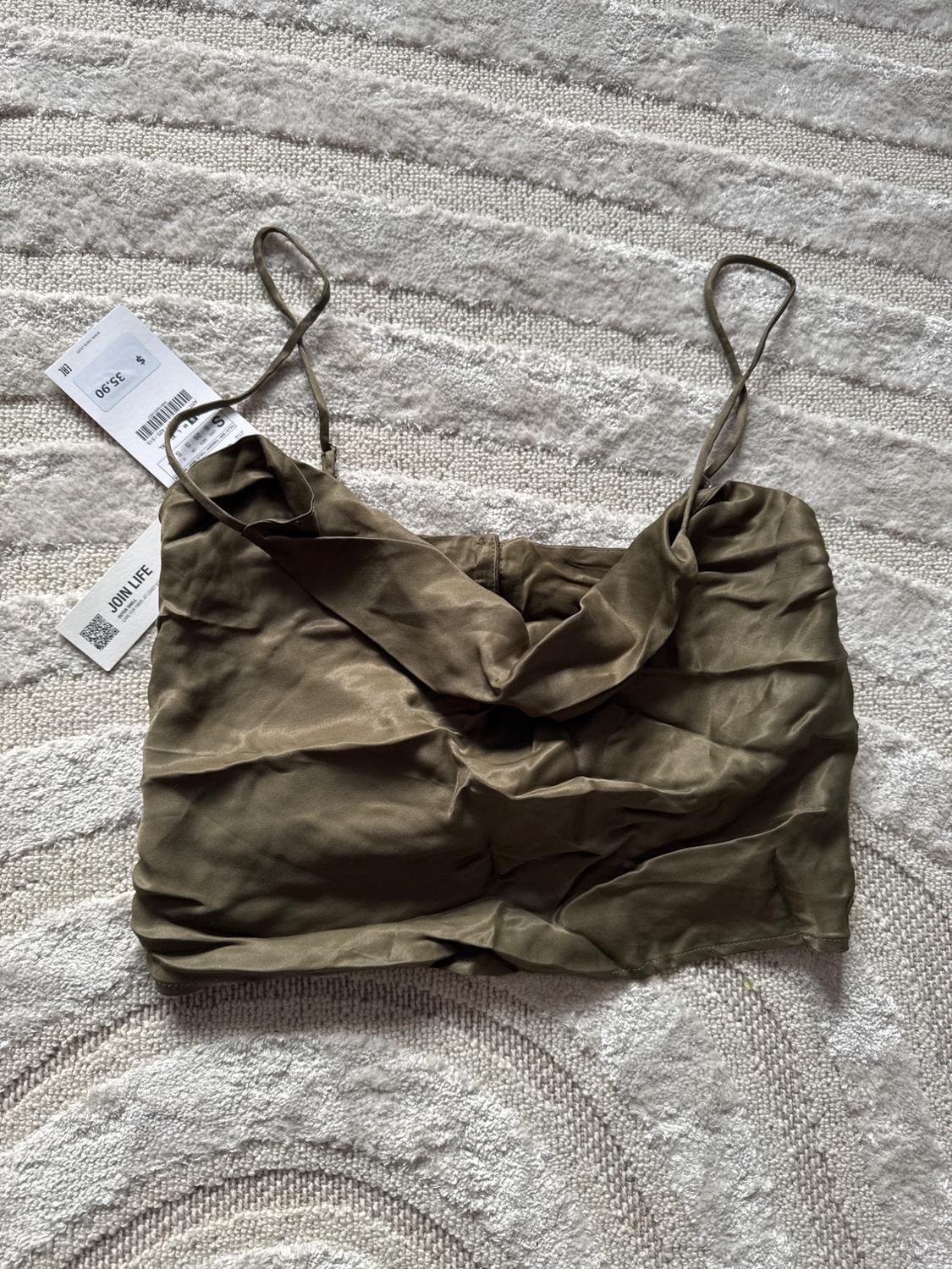 Front view of an olive green cropped top with thin straps and gathering in the centre.