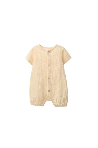 Front view of a beige romper with central button fastening and short sleeves.
