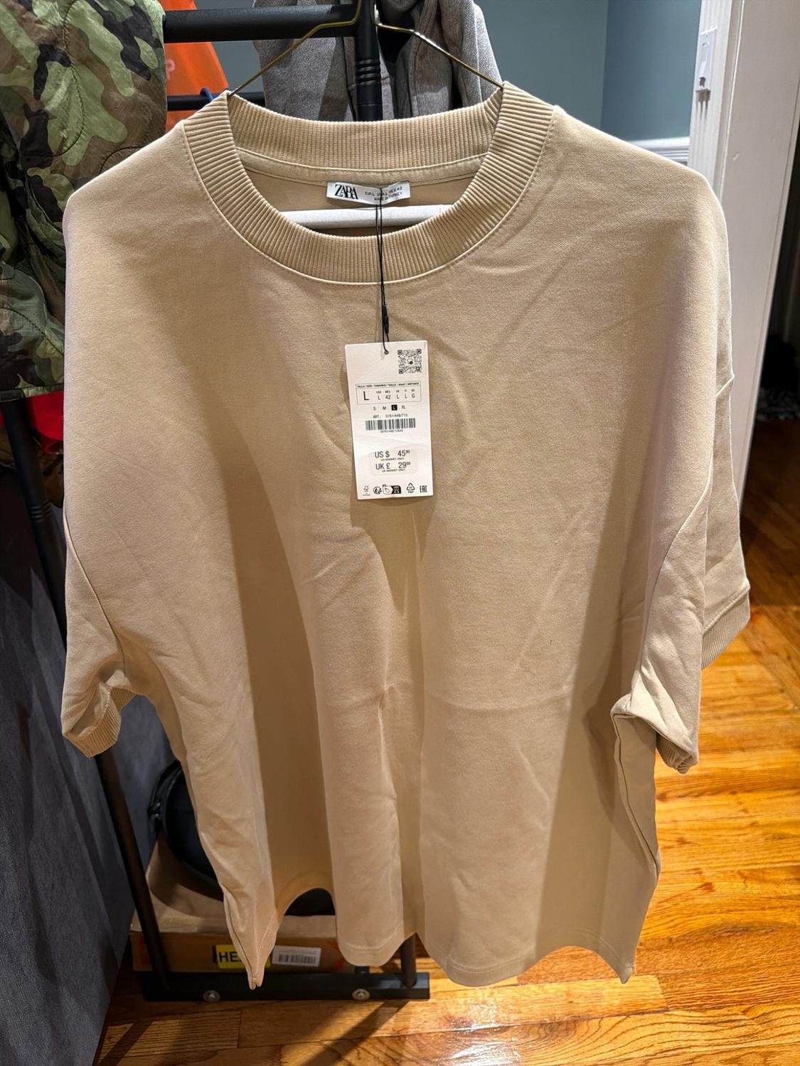 Short-sleeve beige zara T-shirt, ribbed crew neck, hanging on a hanger with a price tag of 45 USD and 29 GBP.
