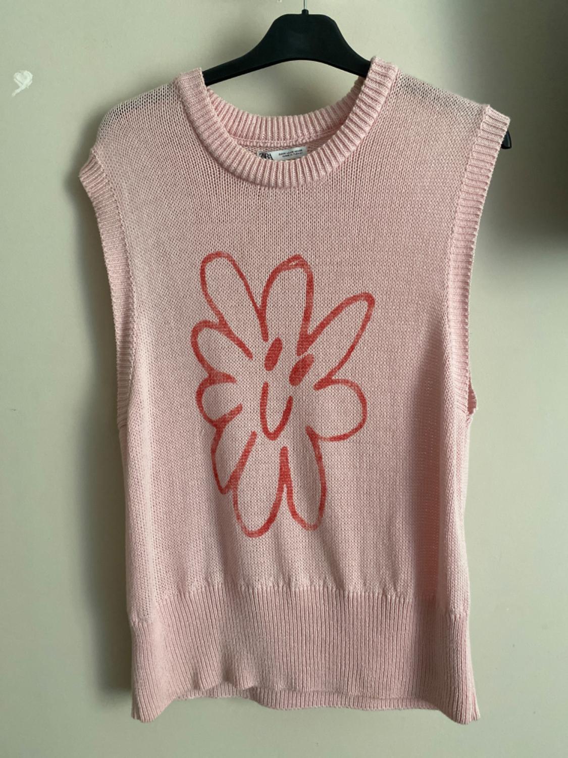 Front view of a pink waistcoat with a red smiling flower print.