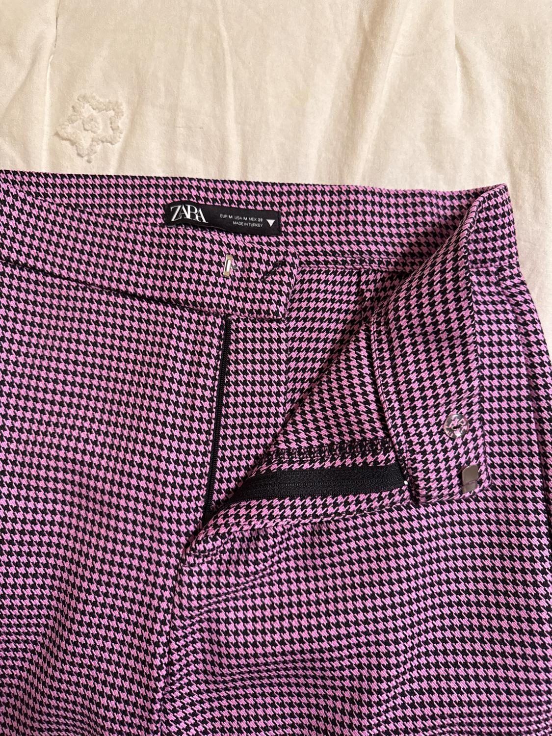 Houndstooth trousers in pink and black, visible zip. Zara label with text "EUR M USA M MEX 28 MADE IN TURKEY".