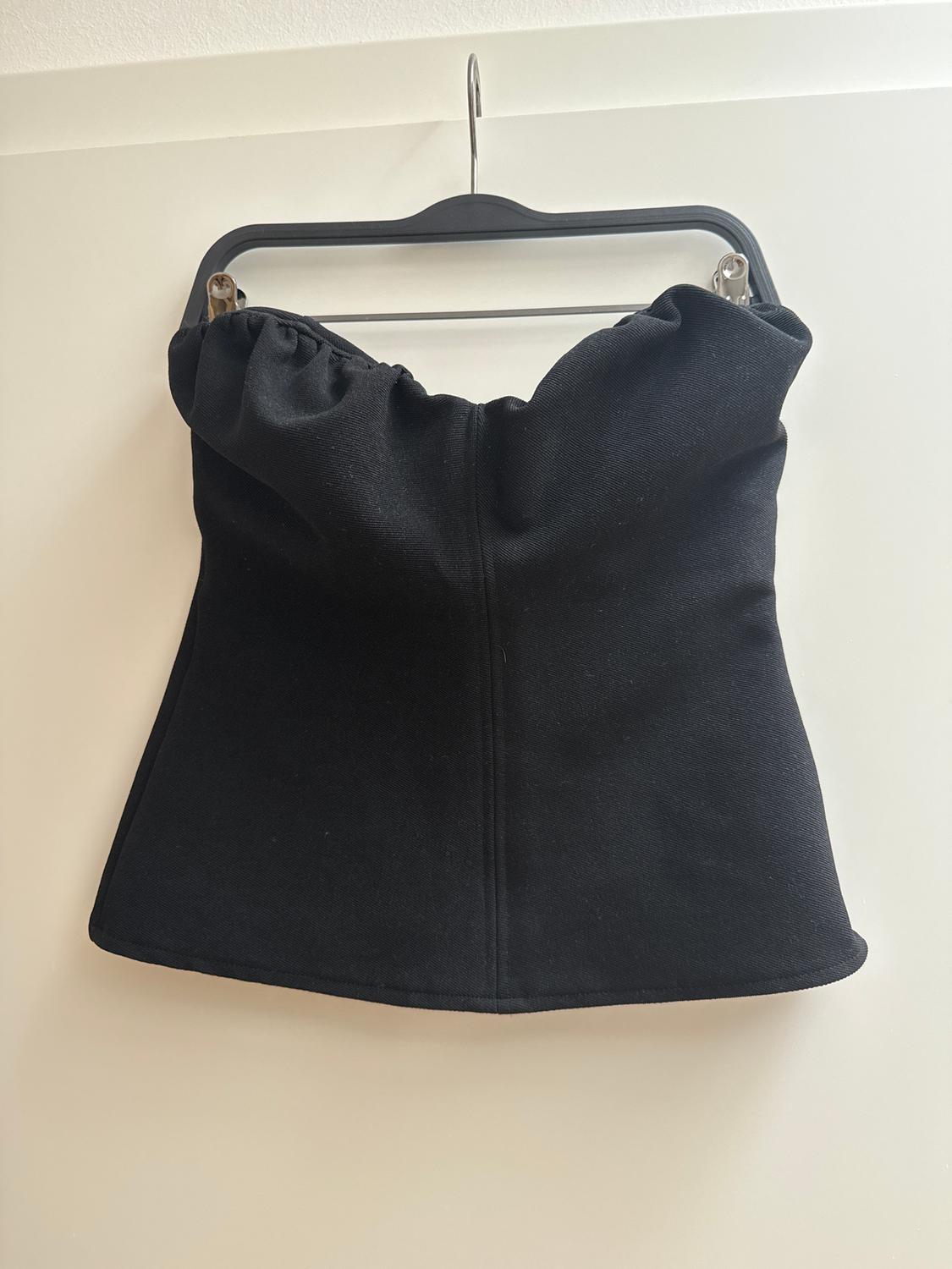 Black strapless top hanging on a black hanger against a white background.