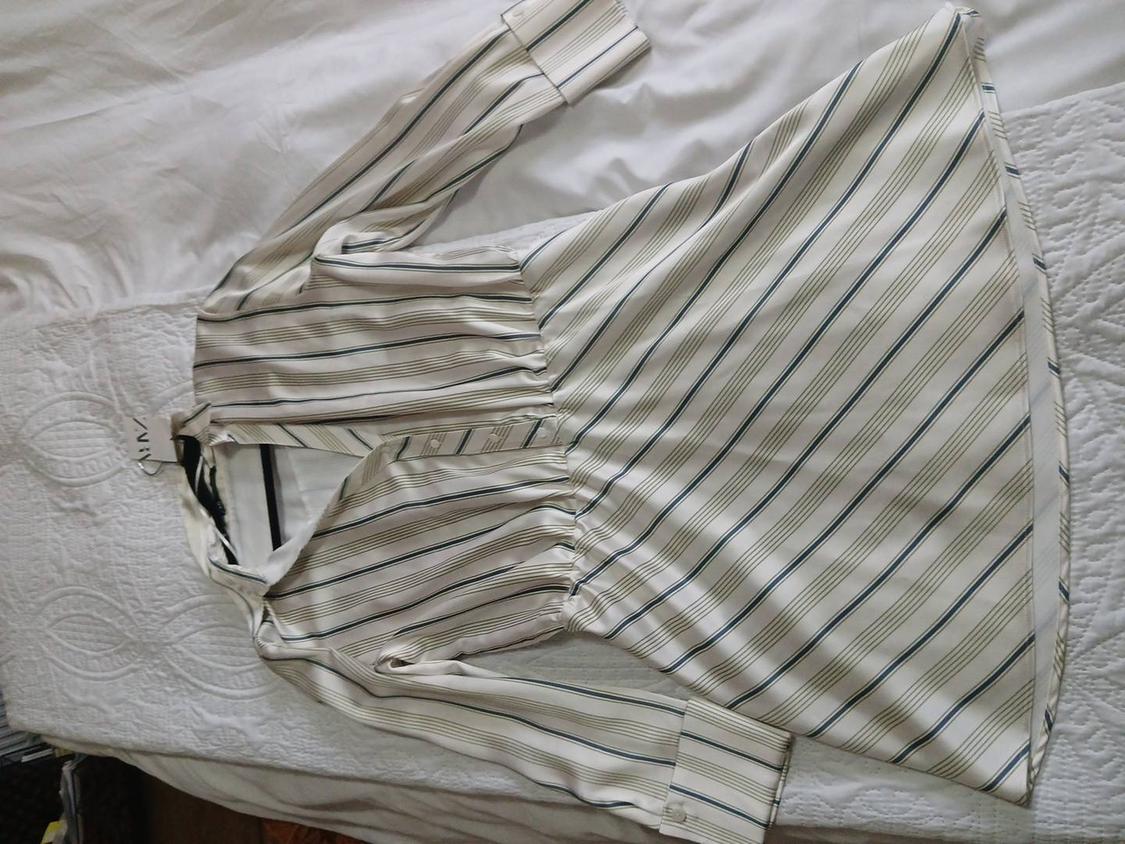 Black and white striped dress with long sleeves and buttons, on a white bed. Visible label on the collar.