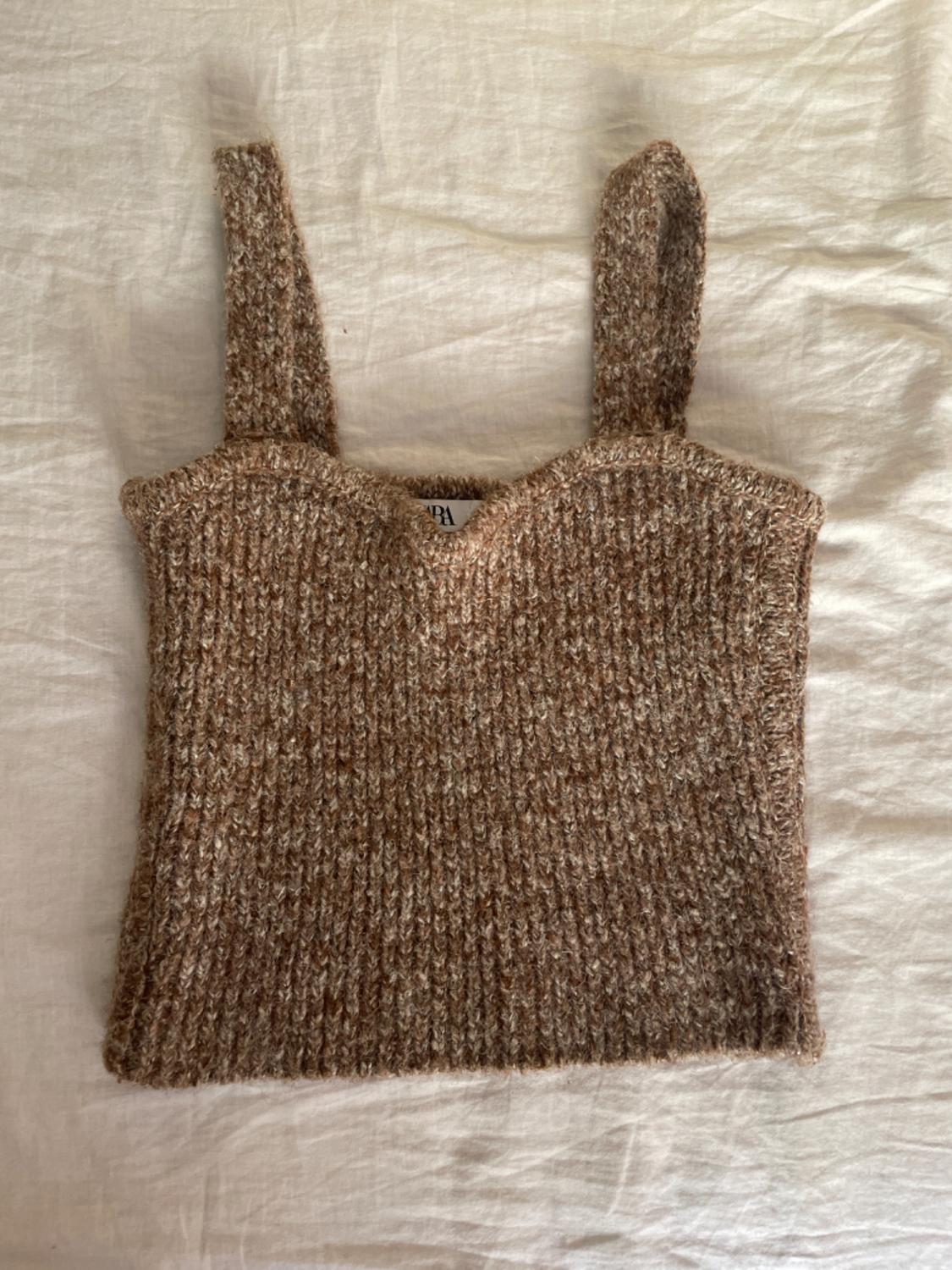 Brown knitted top with wide straps on a white background. Label visible on the inside of the neckline.