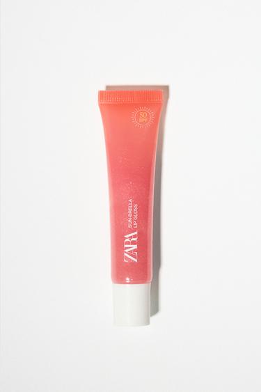 Frontansicht einer Korallenfarbenen SPF 50 Lipgloss-Tube mit dem Text "ZARA Sunbrella Lip Gloss".