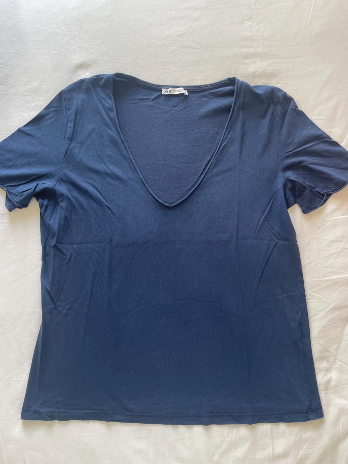 Navy blue short-sleeved V-neck t-shirt, on a white surface. Visible label on the collar.