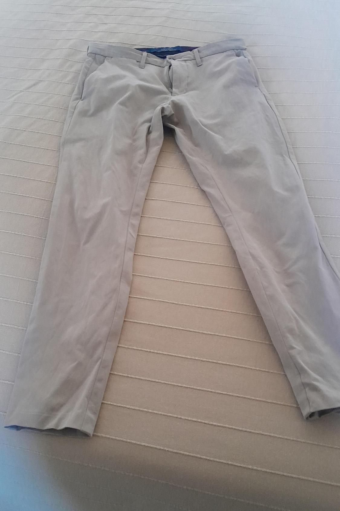 Front view of beige trousers with side pockets and belt loops.