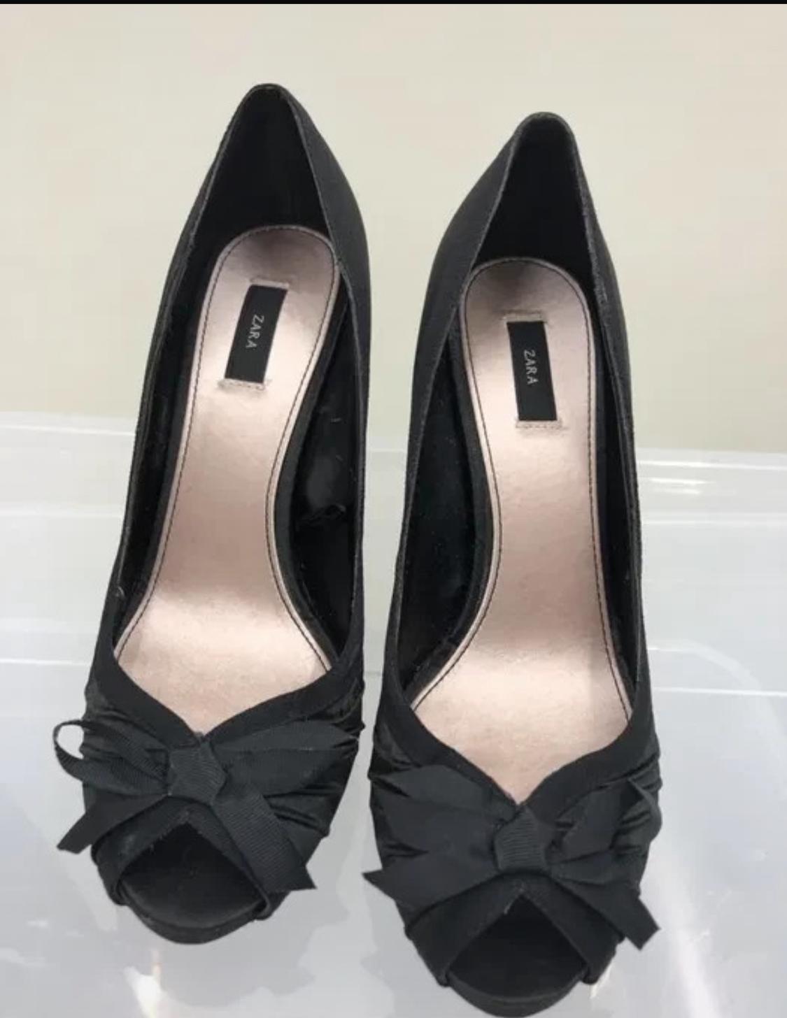 Black high-heeled shoes with a bow on the open toe.