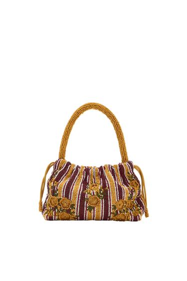 Beaded bag with a mustard-coloured handle and gathered closure. Maroon, white, and yellow stripes with green flowers and leaves. White background.