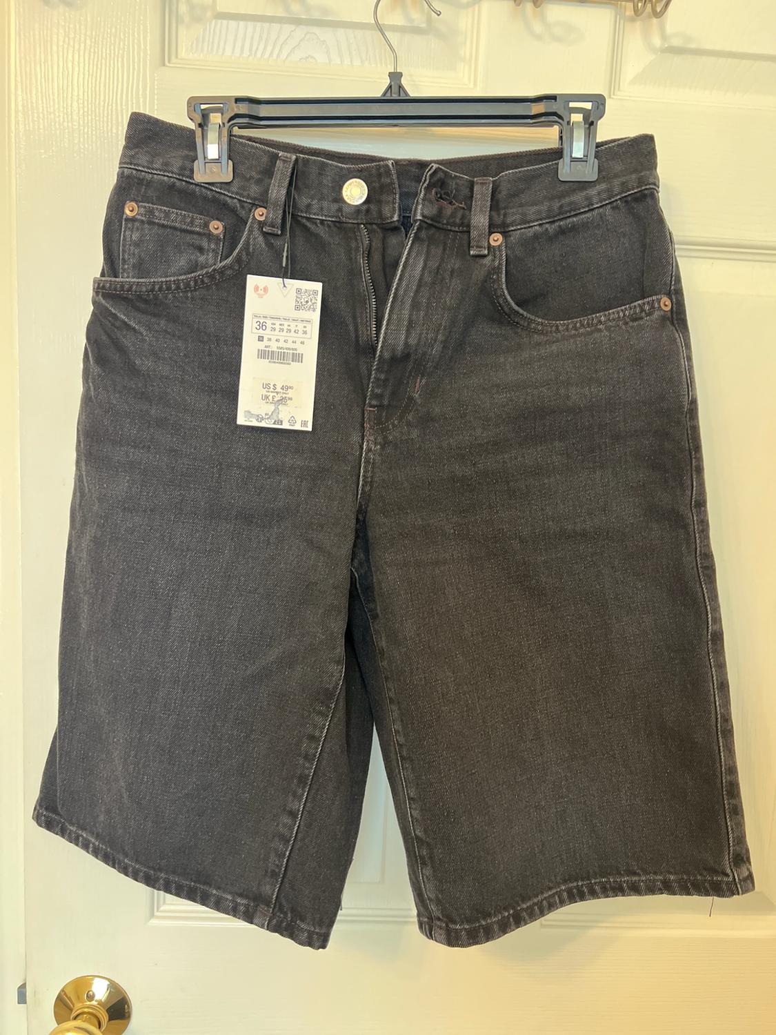 Dark grey denim shorts on a hanger over a white door. Tag with text: 36, US $49.90, UK £29.99.