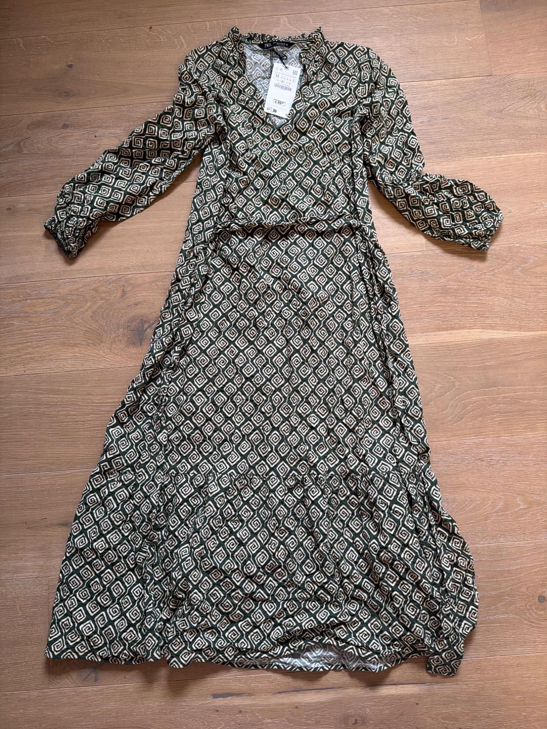 Long dress with a black and white geometric print on a wooden floor. Visible label on the collar.