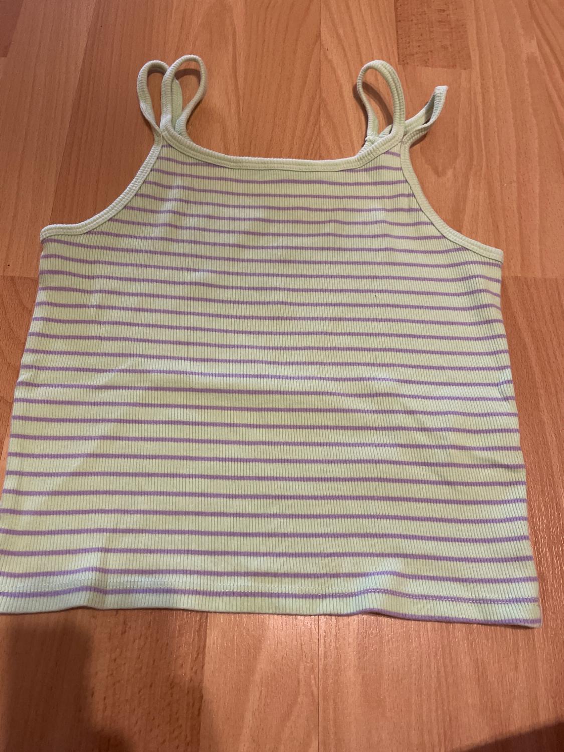 Vest top with horizontal stripes in shades of green and lilac on a light wood background.