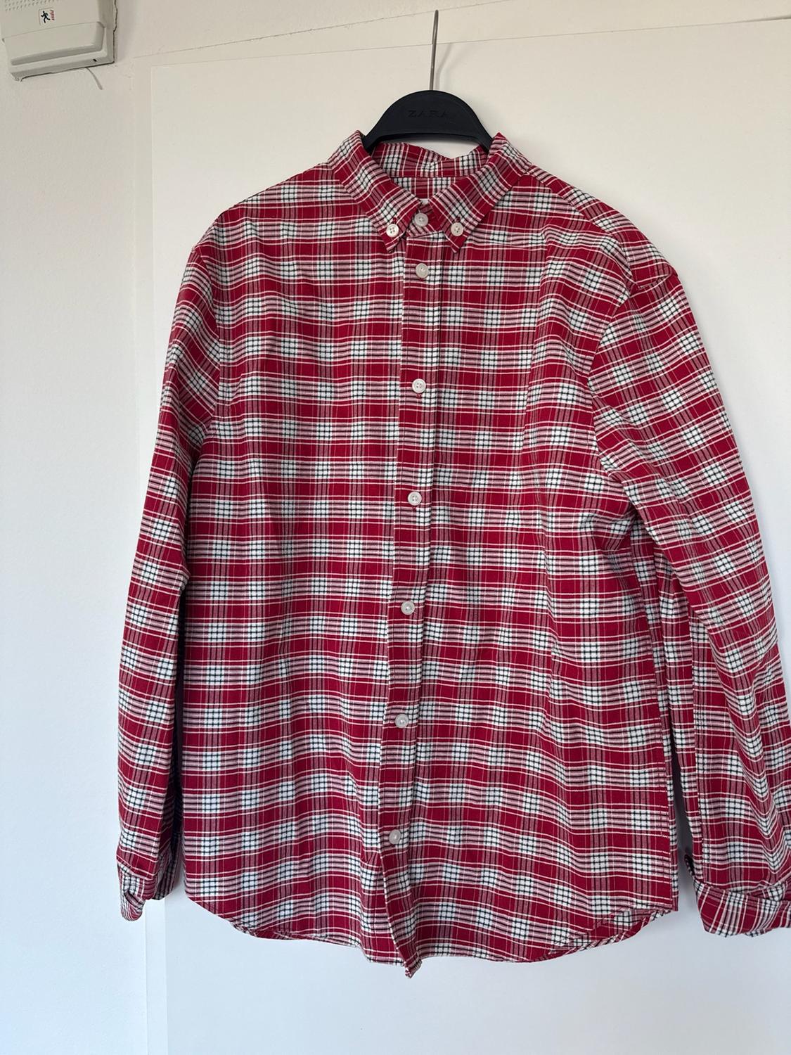 Red, white, and black long-sleeved plaid shirt hanging on a black hanger with the text ZARA on a white background.