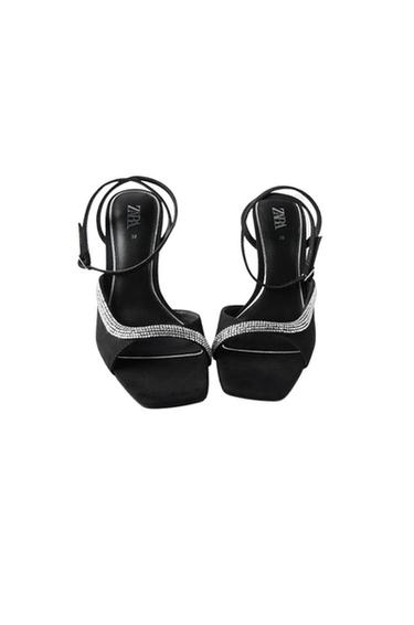Front view of black sandals with sparkly straps and an adjustable buckle.