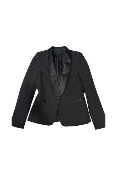 Women's black jacket with satin lapel and one front button. Elegant and modern design on a white background.