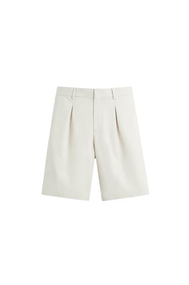 White Bermuda shorts with pleats and belt loops, white background.