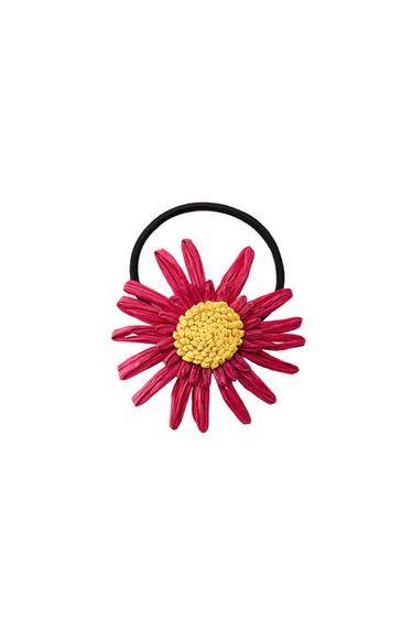 Front view of a hair bobble with a red flower and yellow centre