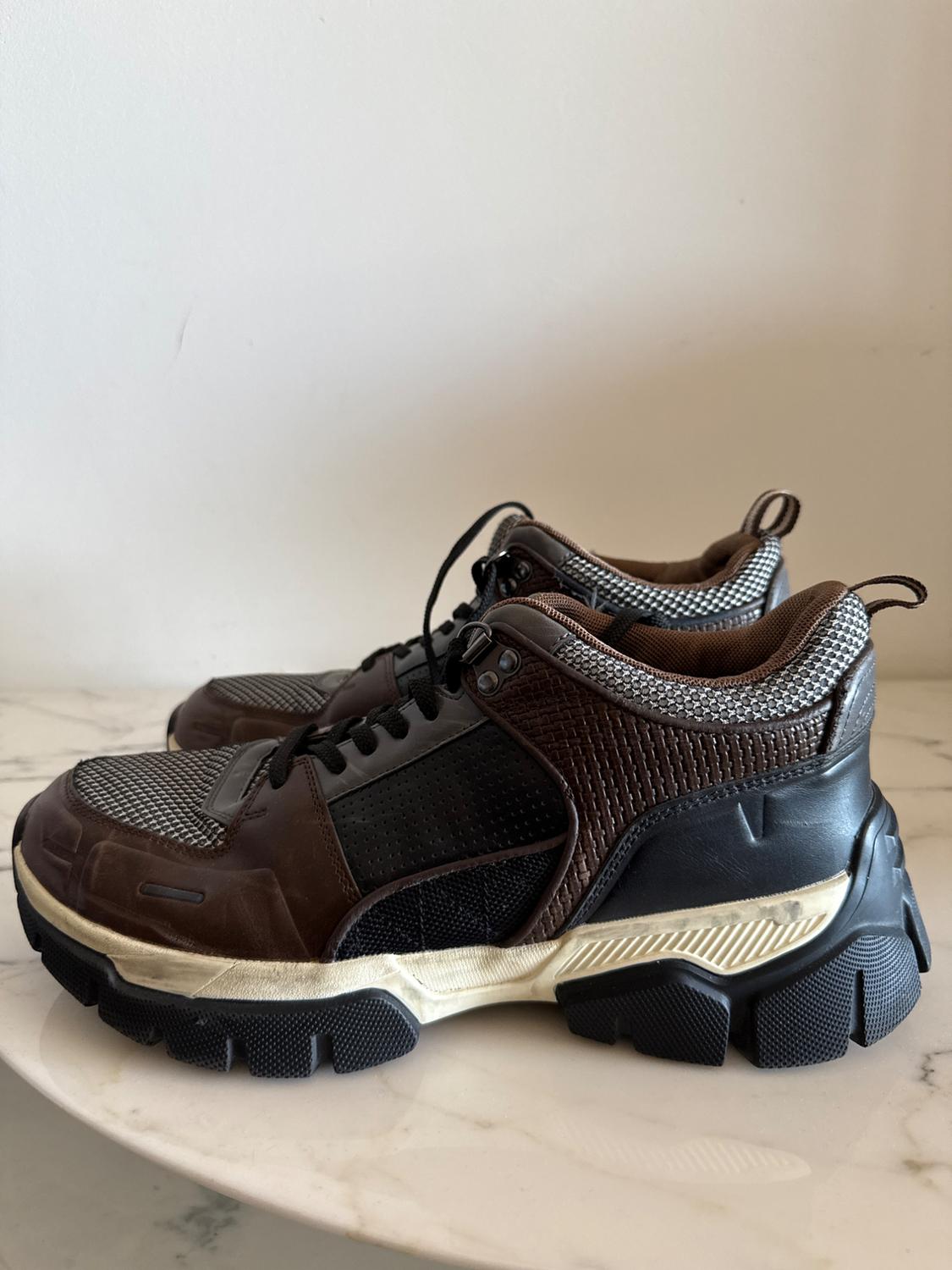 Side view of brown and black trainers with a thick black sole and mesh detailing.