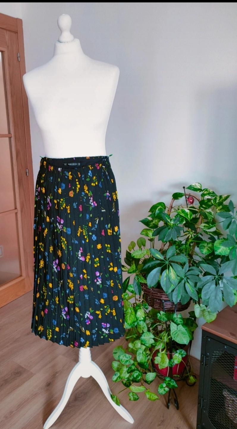 Front view of a black pleated skirt with a multicoloured floral print.