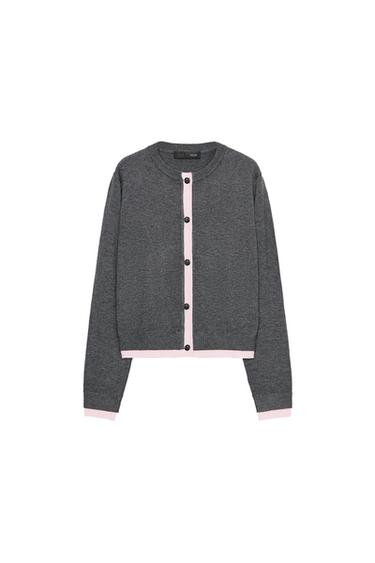 Front view of a grey jacket with a crew neck, long sleeves, and a front fastening with black buttons. Pink ribbed detailing.