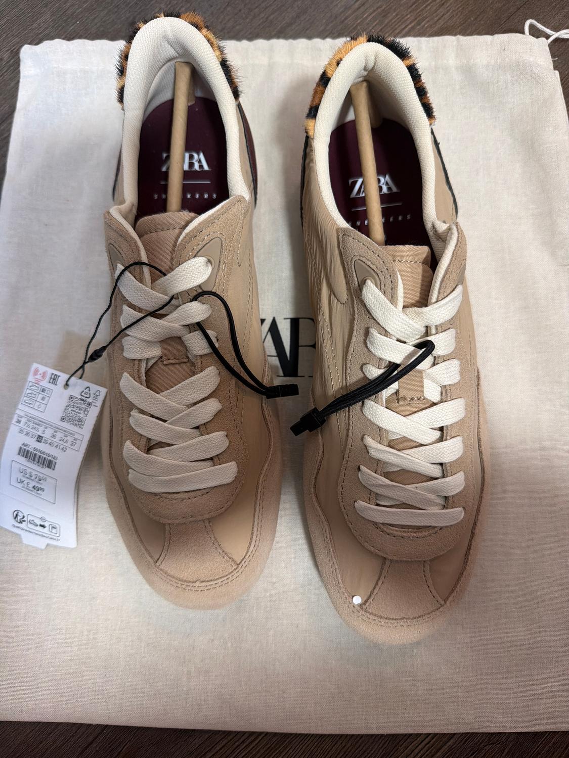 Beige sneakers with white laces on a canvas bag. Label detail and animal print back. Visible text: "ZARA".