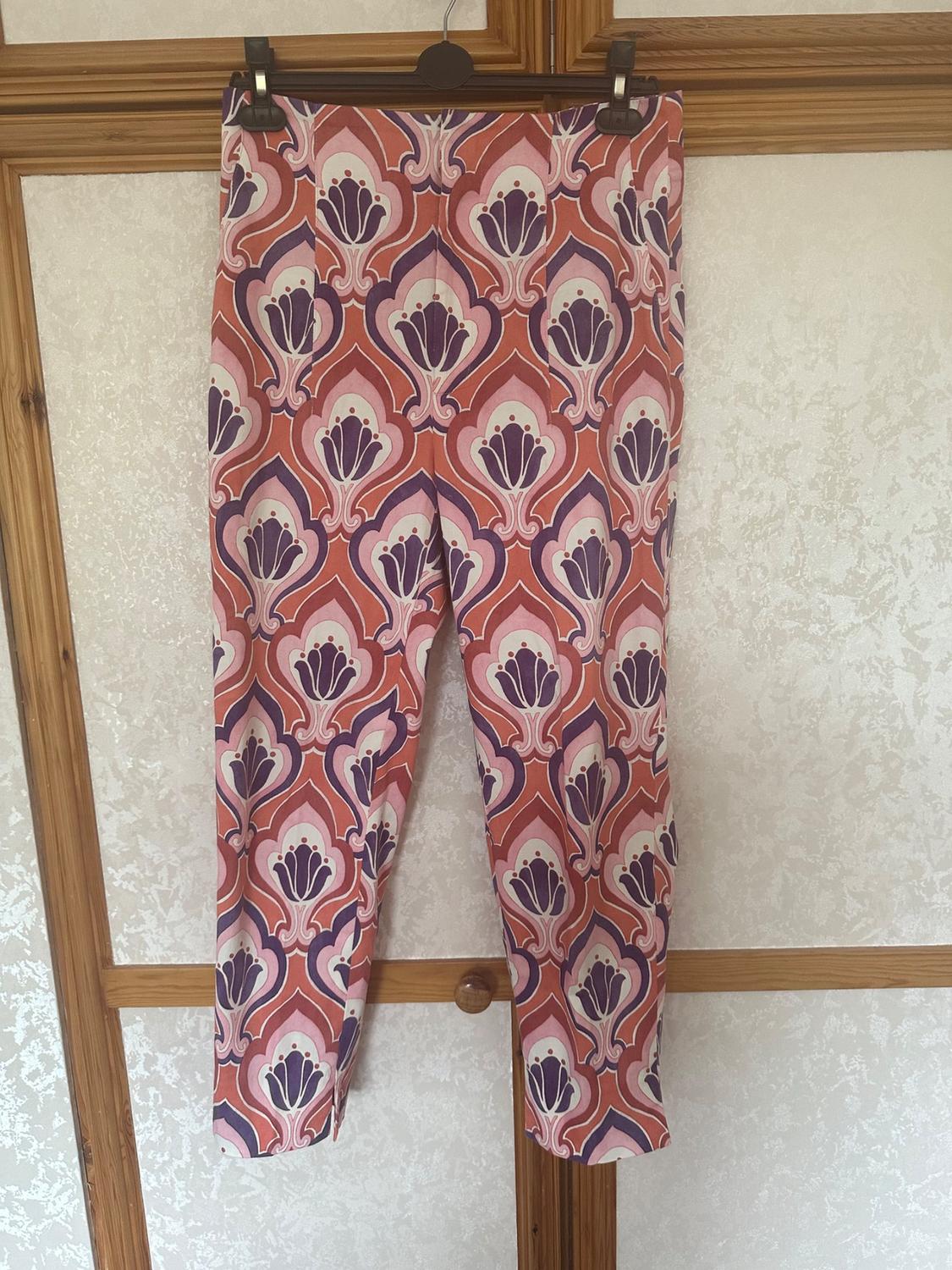 Front view of trousers with geometric print in shades of pink, purple and white.
