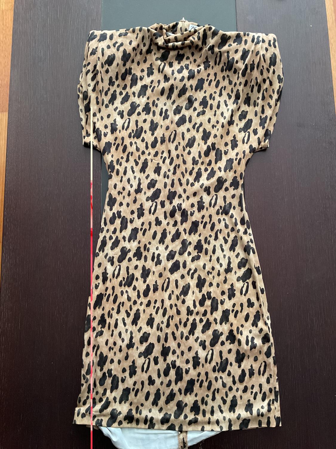Short-sleeved dress with a leopard print in brown and black tones, on a dark wooden table.