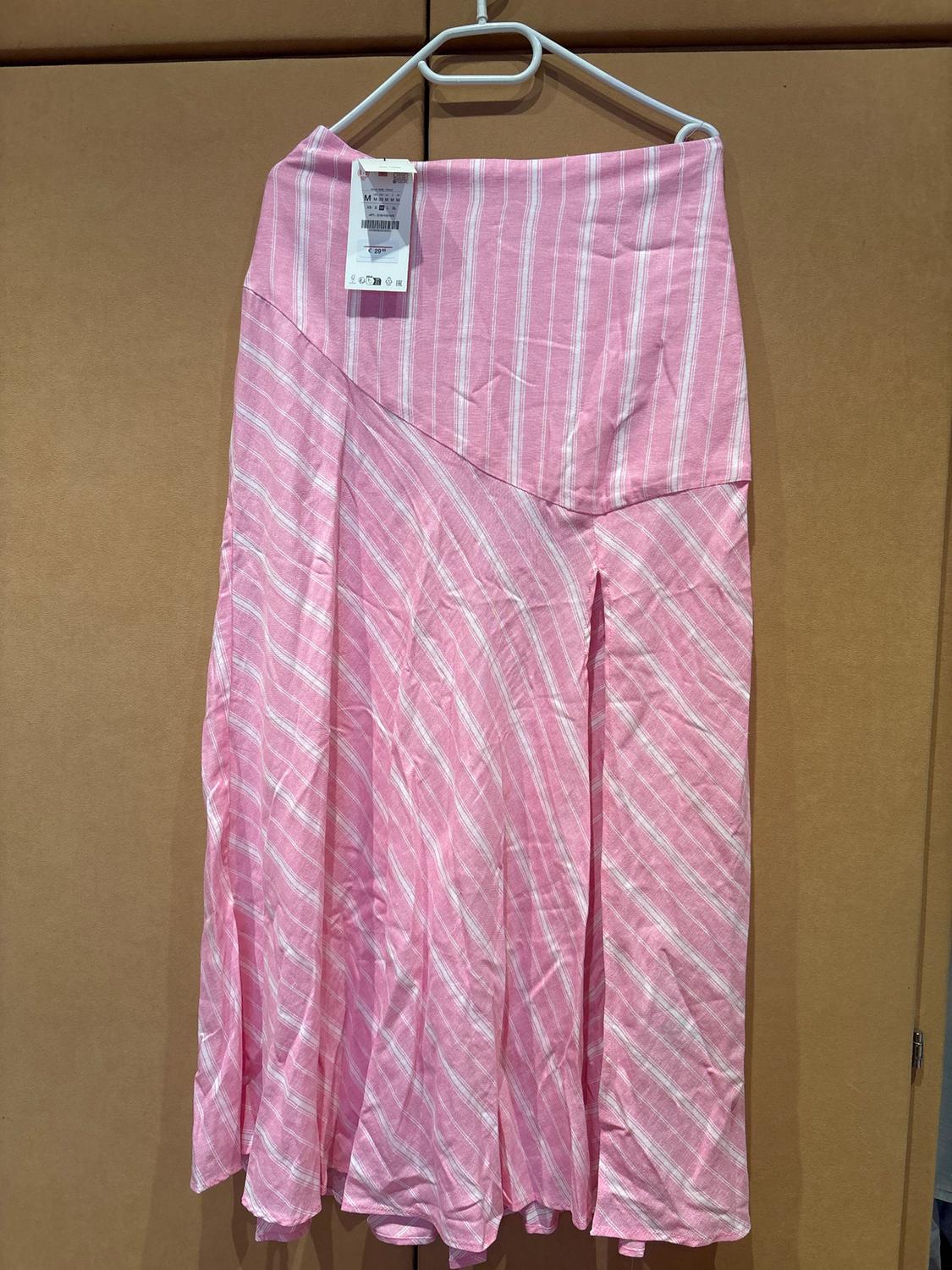 Long pink skirt with white vertical stripes, hanging on a white hanger. Label visible in the top left.
